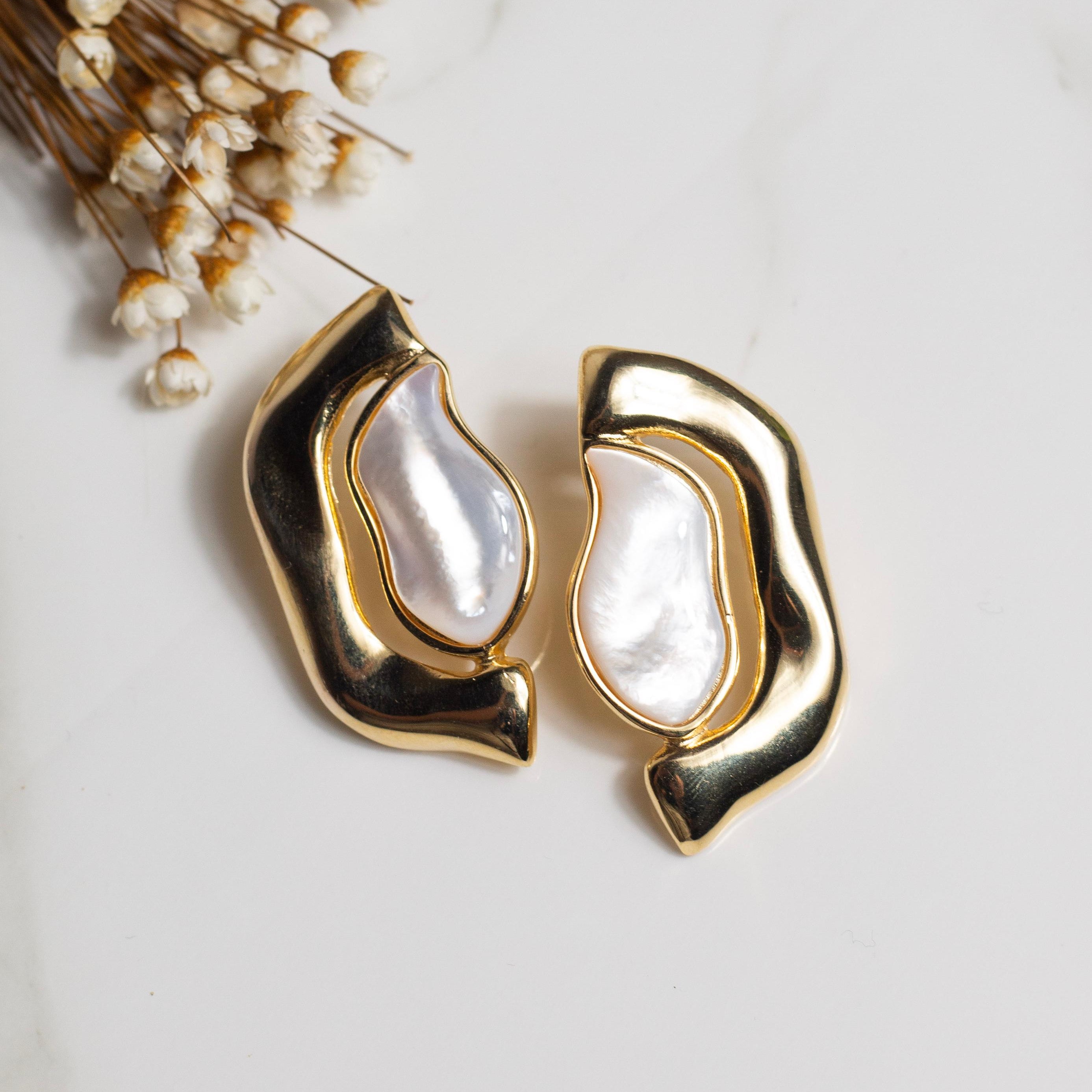Gold hoop earrings with nacre gemstone on a light background
