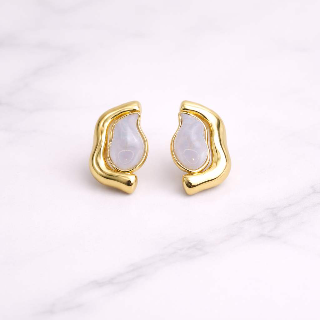 Gold earrings with nacre gemstone on a light background