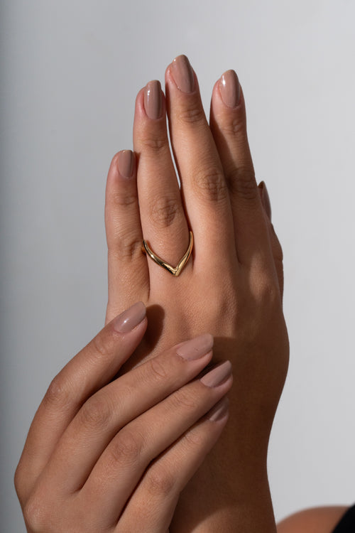Two hands with a gold ring on a neutral background