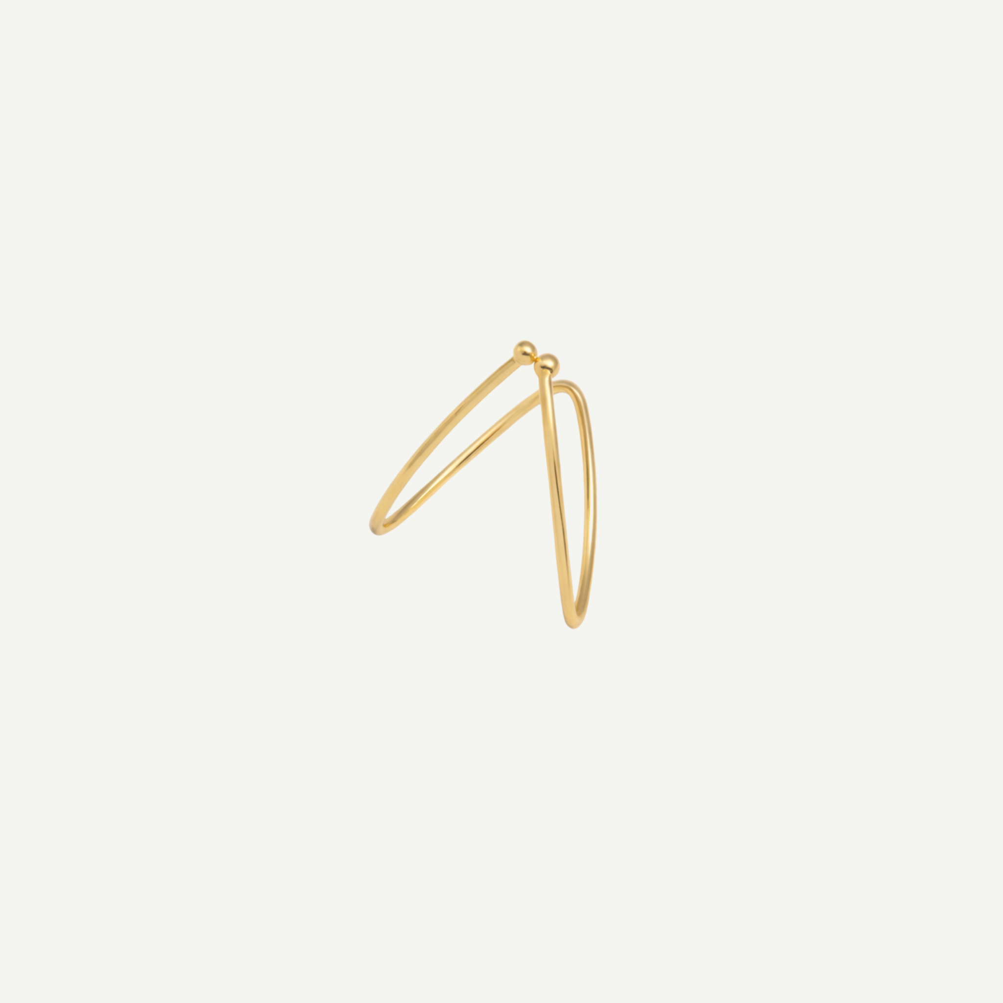 Gold earring on a light beige background