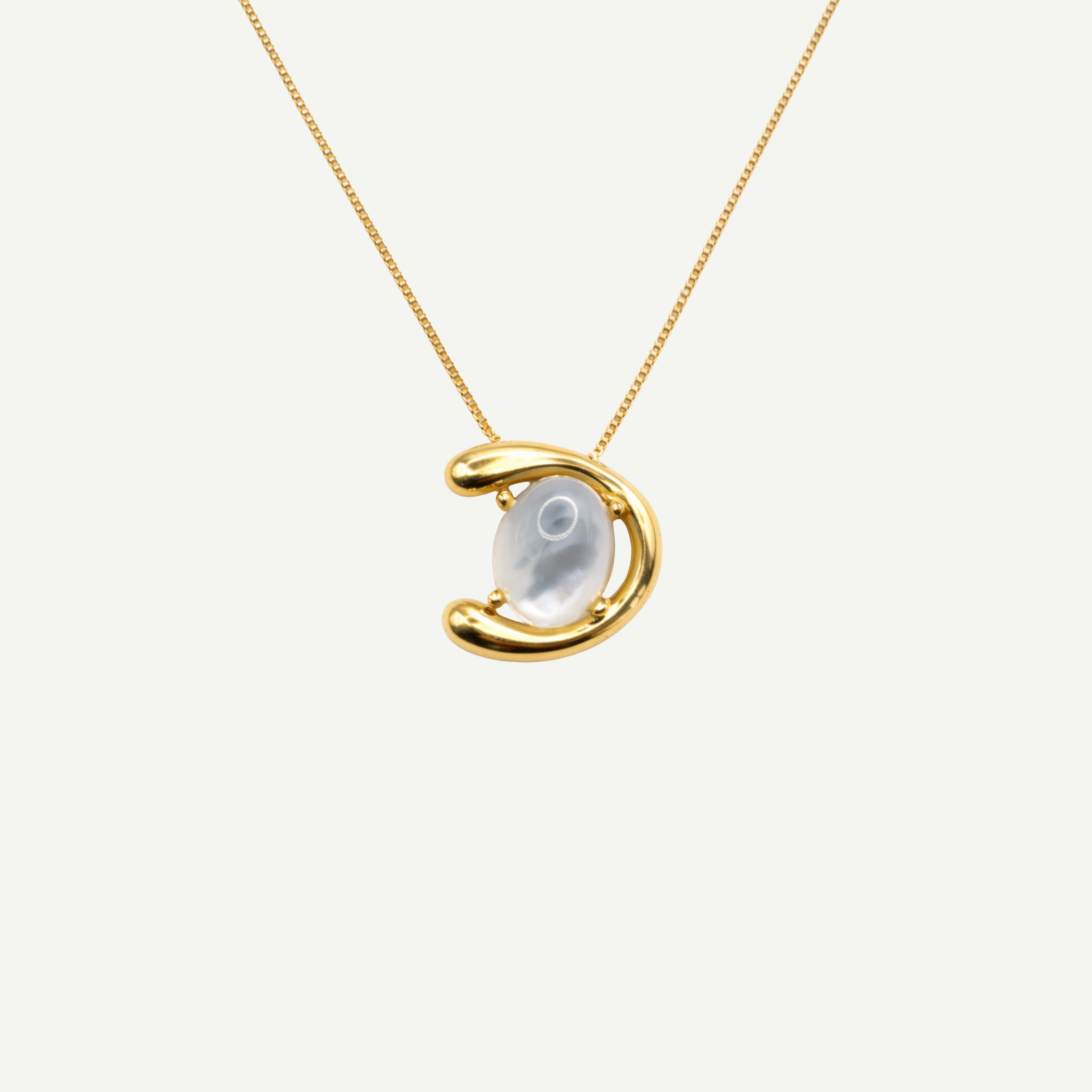 Gold necklace with a half-moon pendant and nacre gemstone on a white background