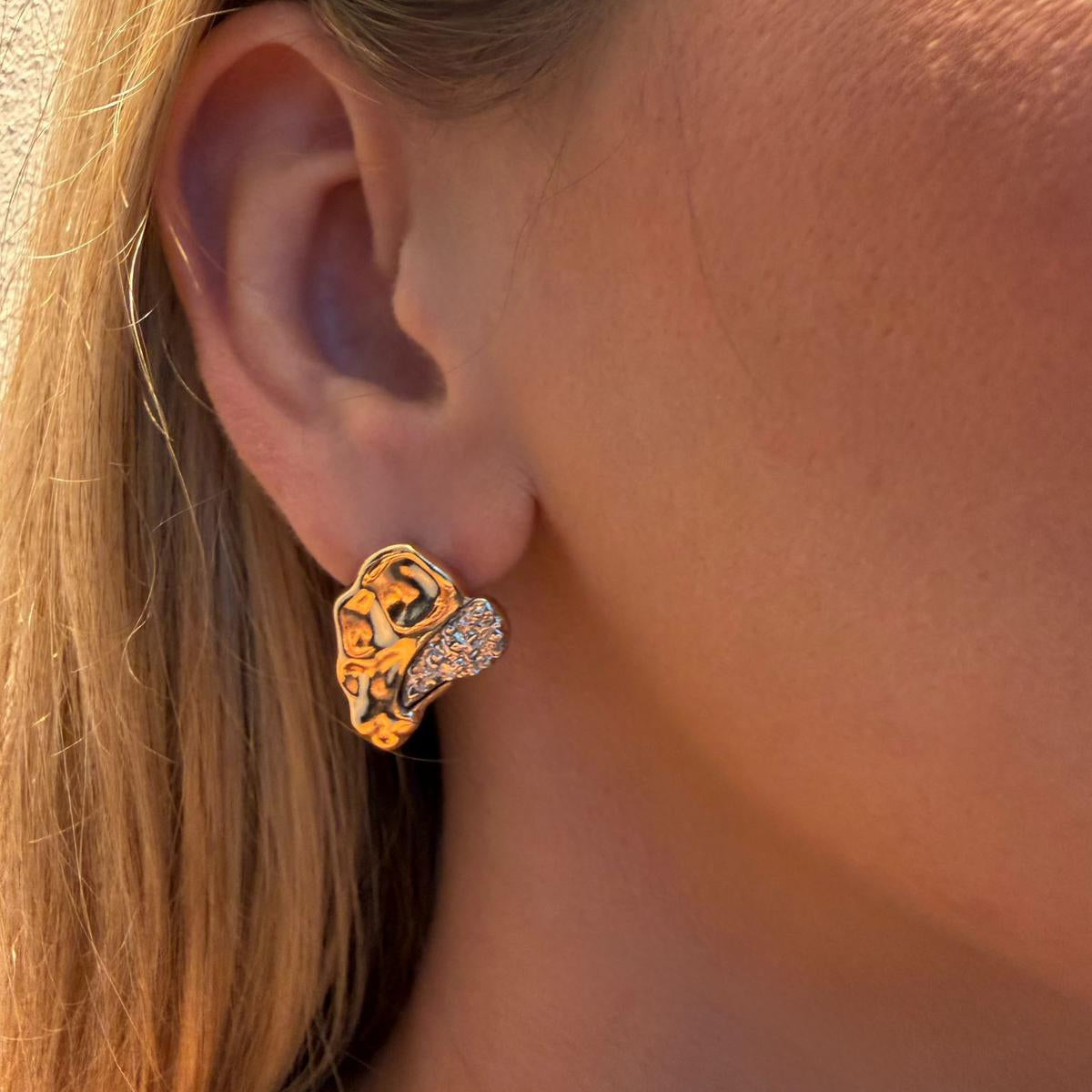 Close-up of an ear wearing a gold and silver earring.