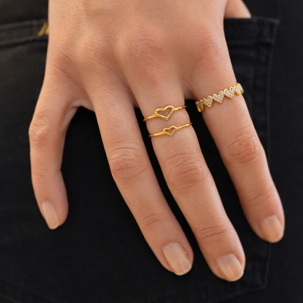 Hand wearing gold heart-shaped rings with a blurred background