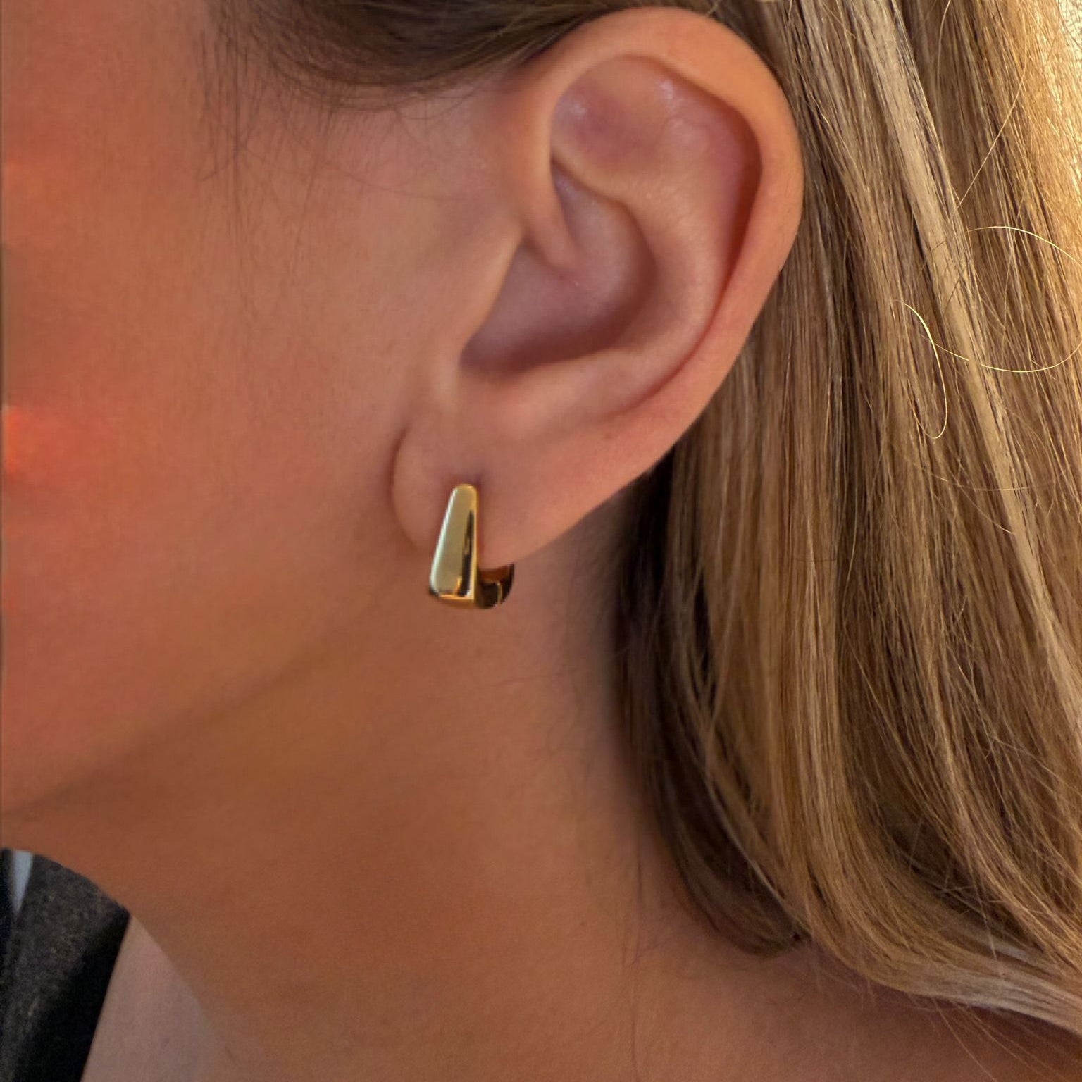 Close-up of a person wearing a gold earring.