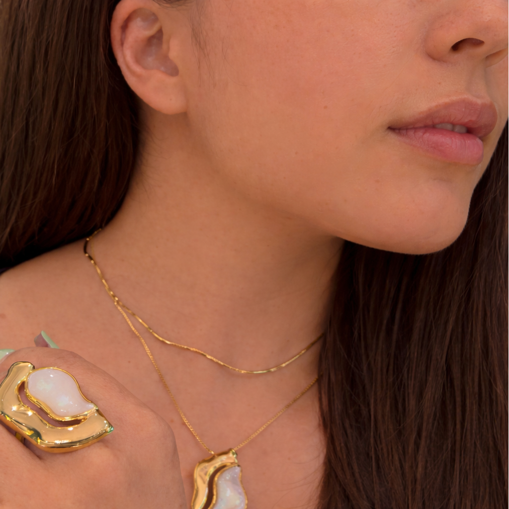 Close-up of a person wearing gold jewelry with a natural background
