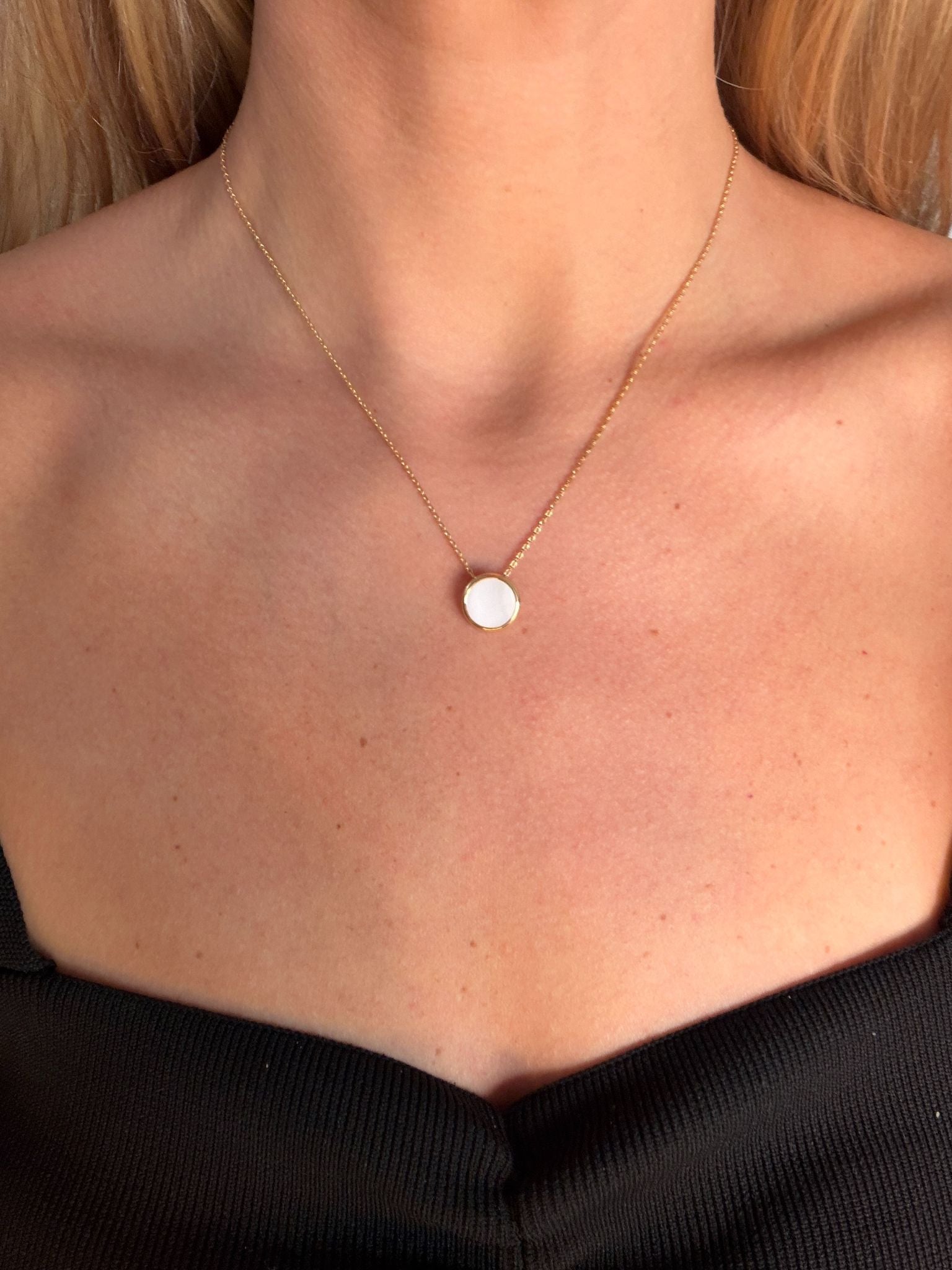 Necklace with a round nacre pendant worn by a person