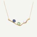 Gold necklace with three gemstones on a white background
