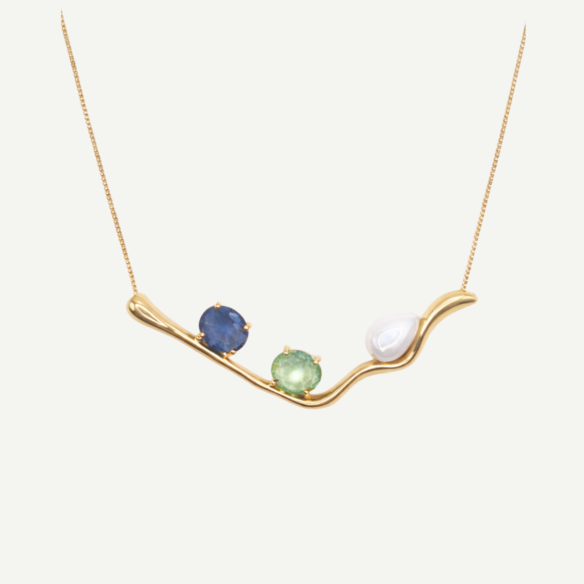 Gold necklace with three gemstones on a white background