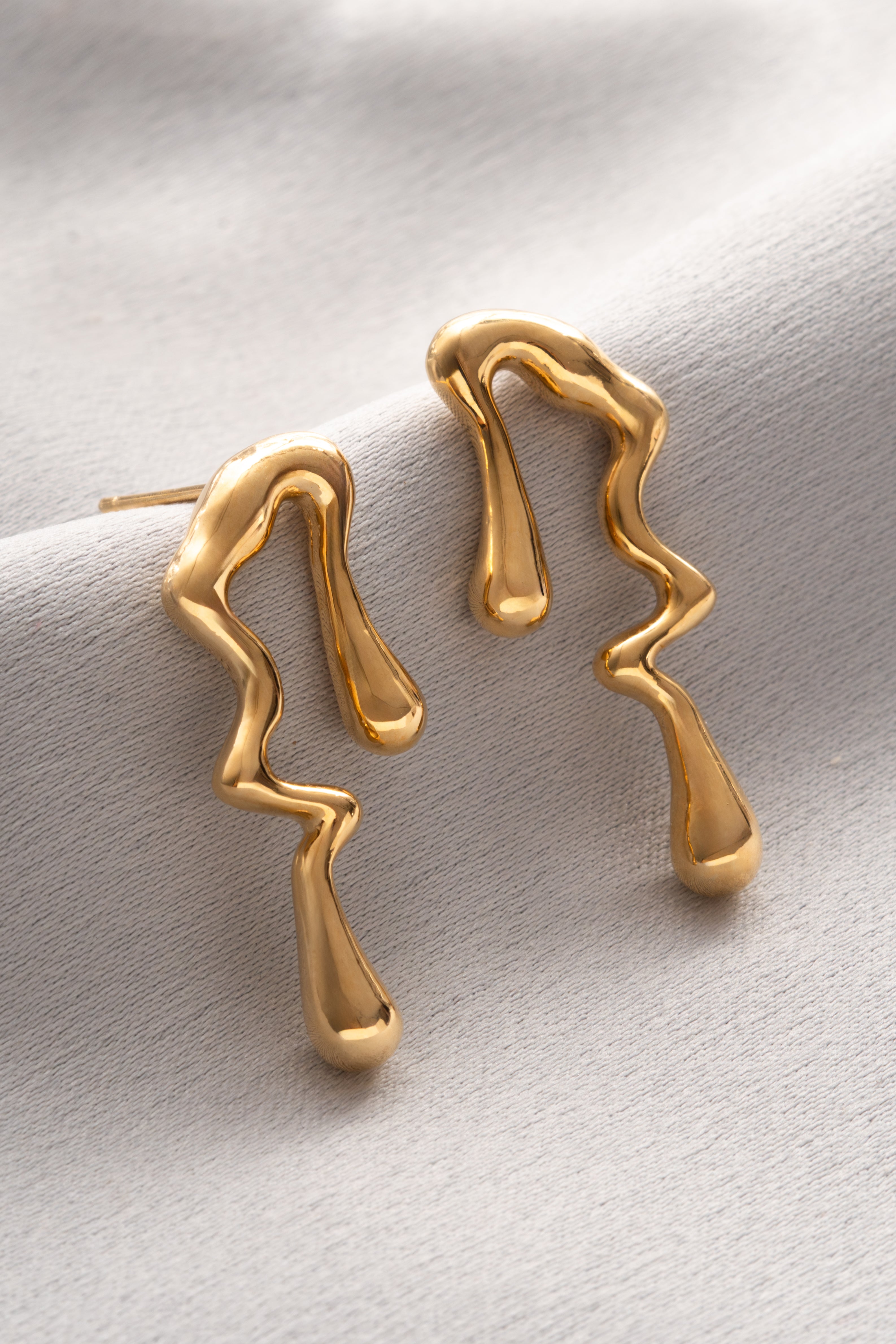 Gold earrings on a light gray background