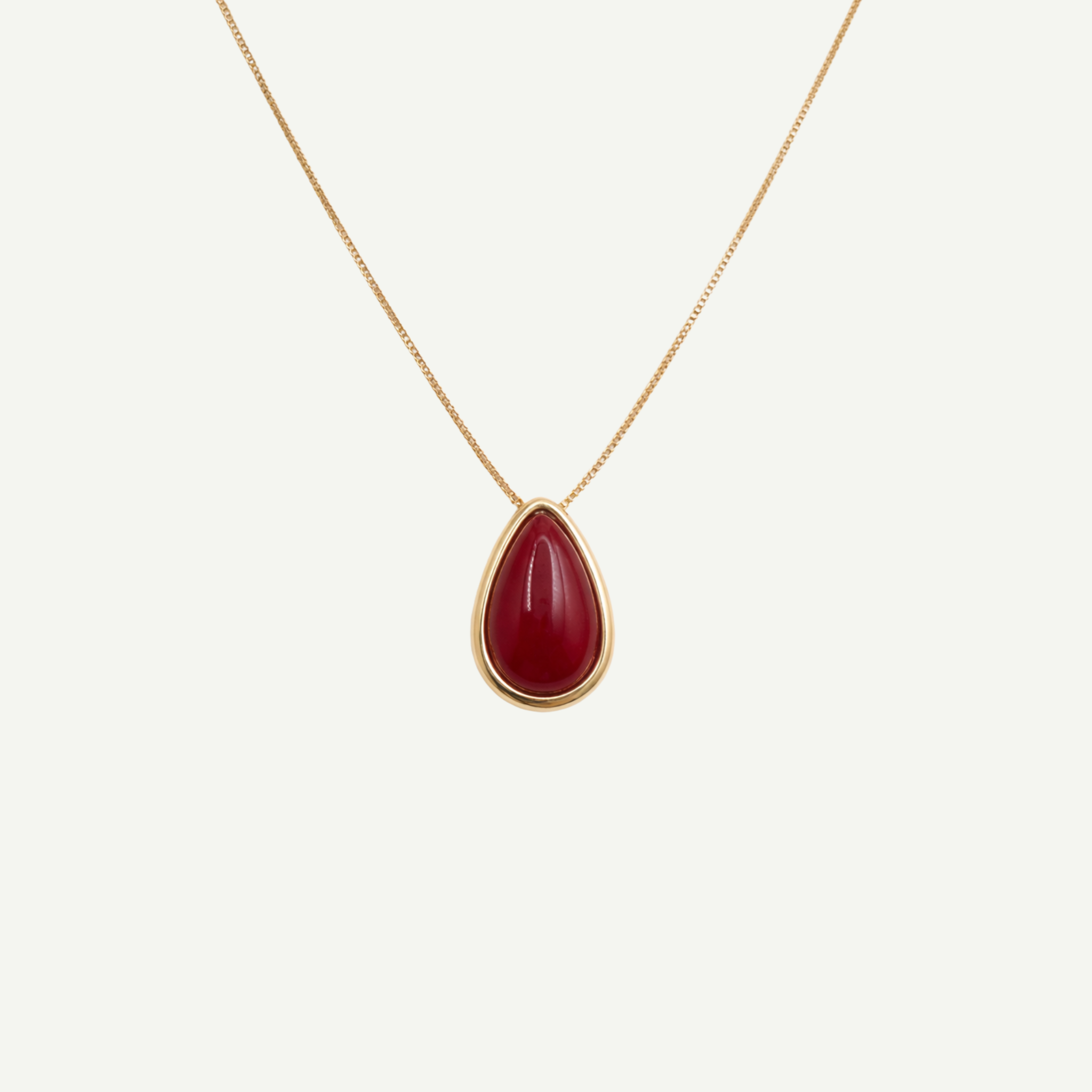 Gold necklace with a natural agate red teardrop pendant on a white background