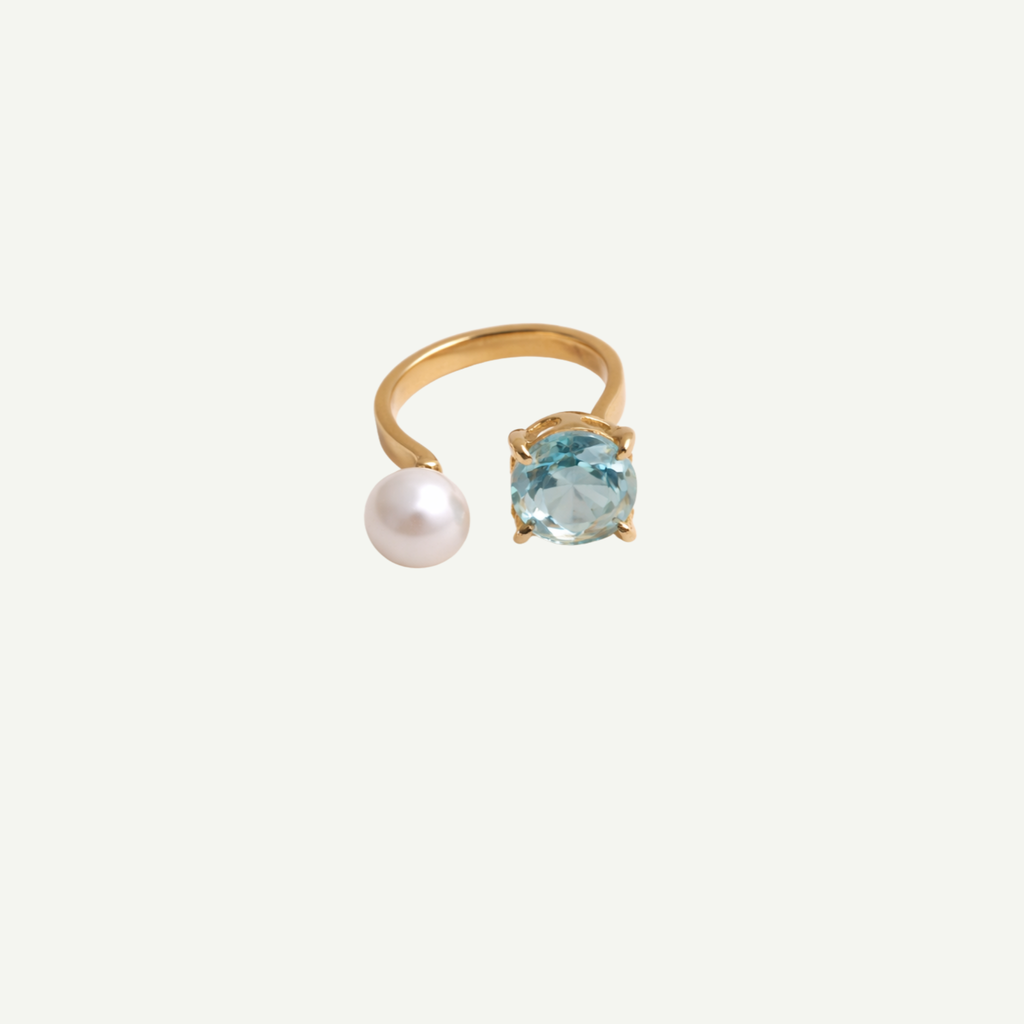 Gold ring with a pearl and blue gemstone on a white background
