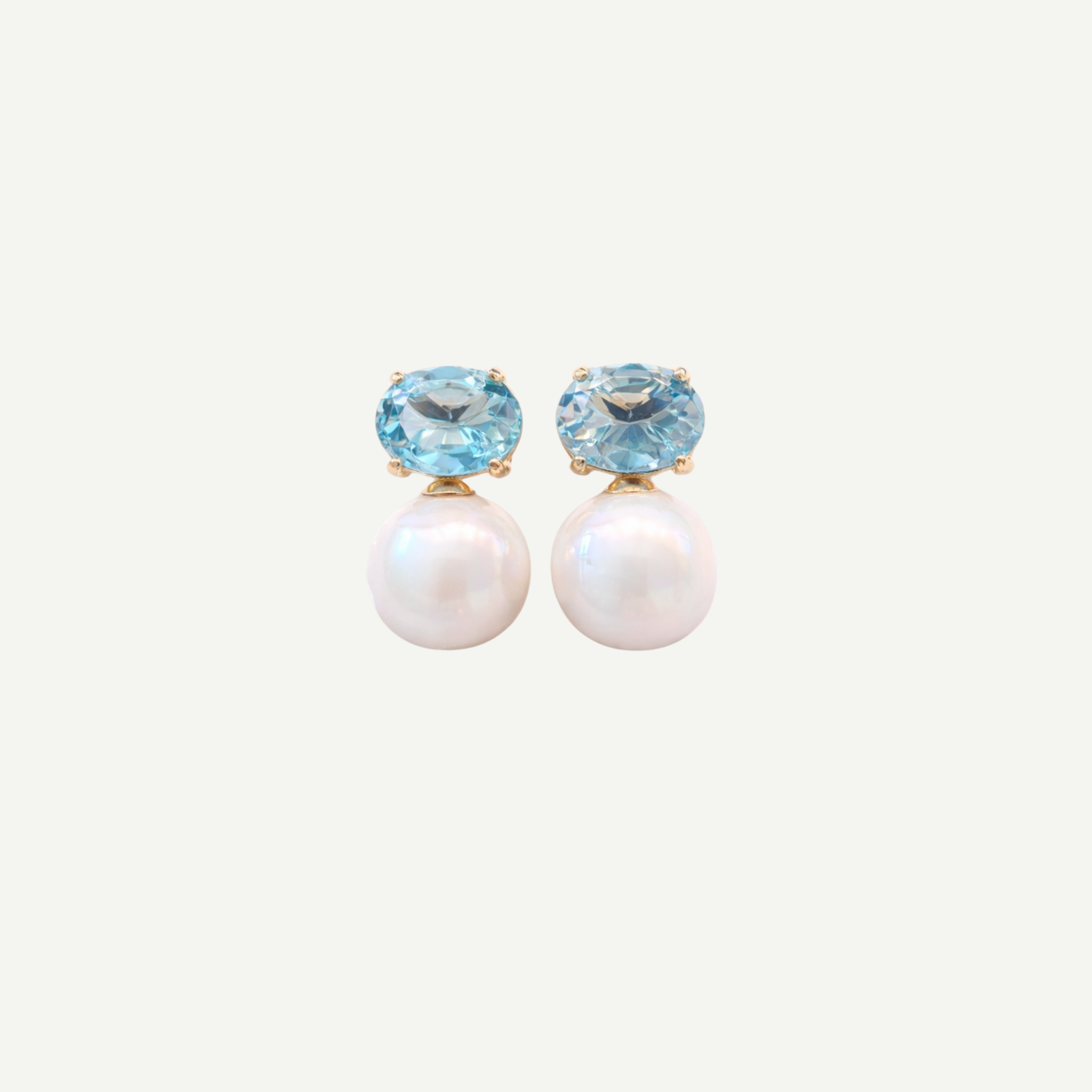 Pair of earrings with blue gemstones and pearl-like centers on a white background