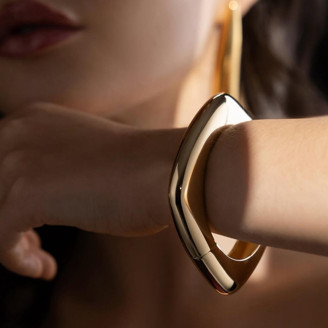 Close-up of a person wearing a gold bracelet on a blurred background