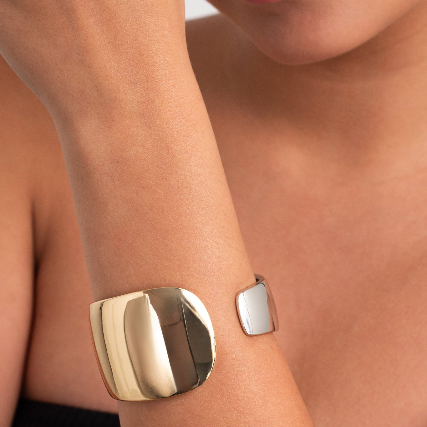 Gold and silver bracelet on a person's wrist with a neutral background