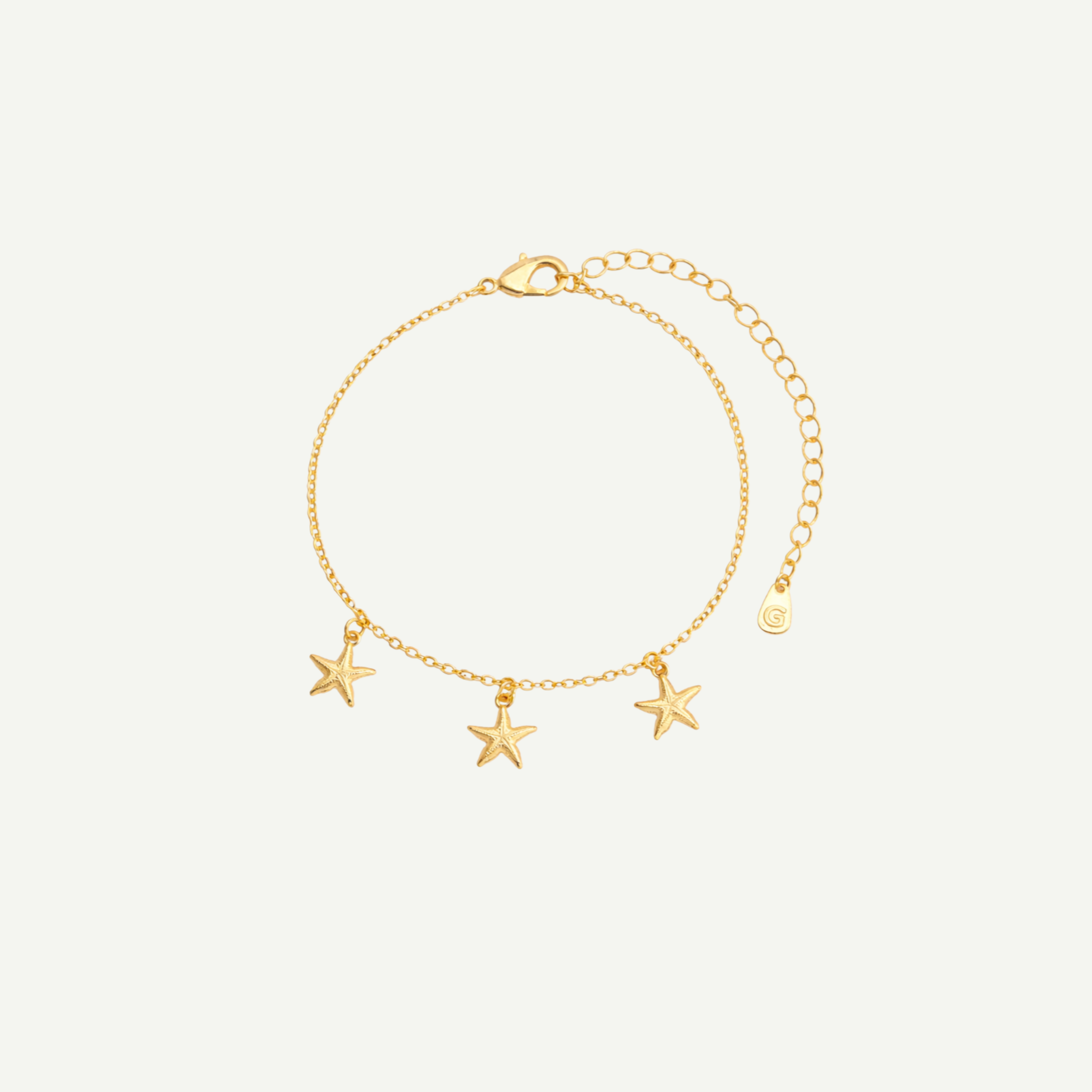 Gold bracelet with star charms on a light beige background