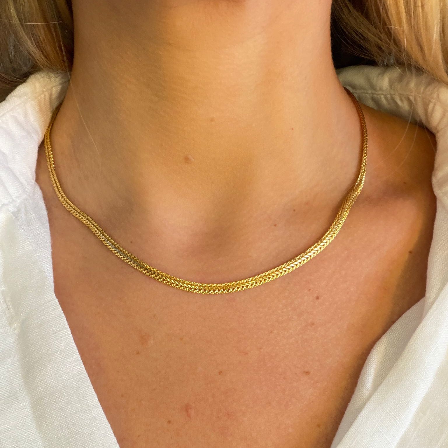 Gold chain necklace on a person wearing a white shirt