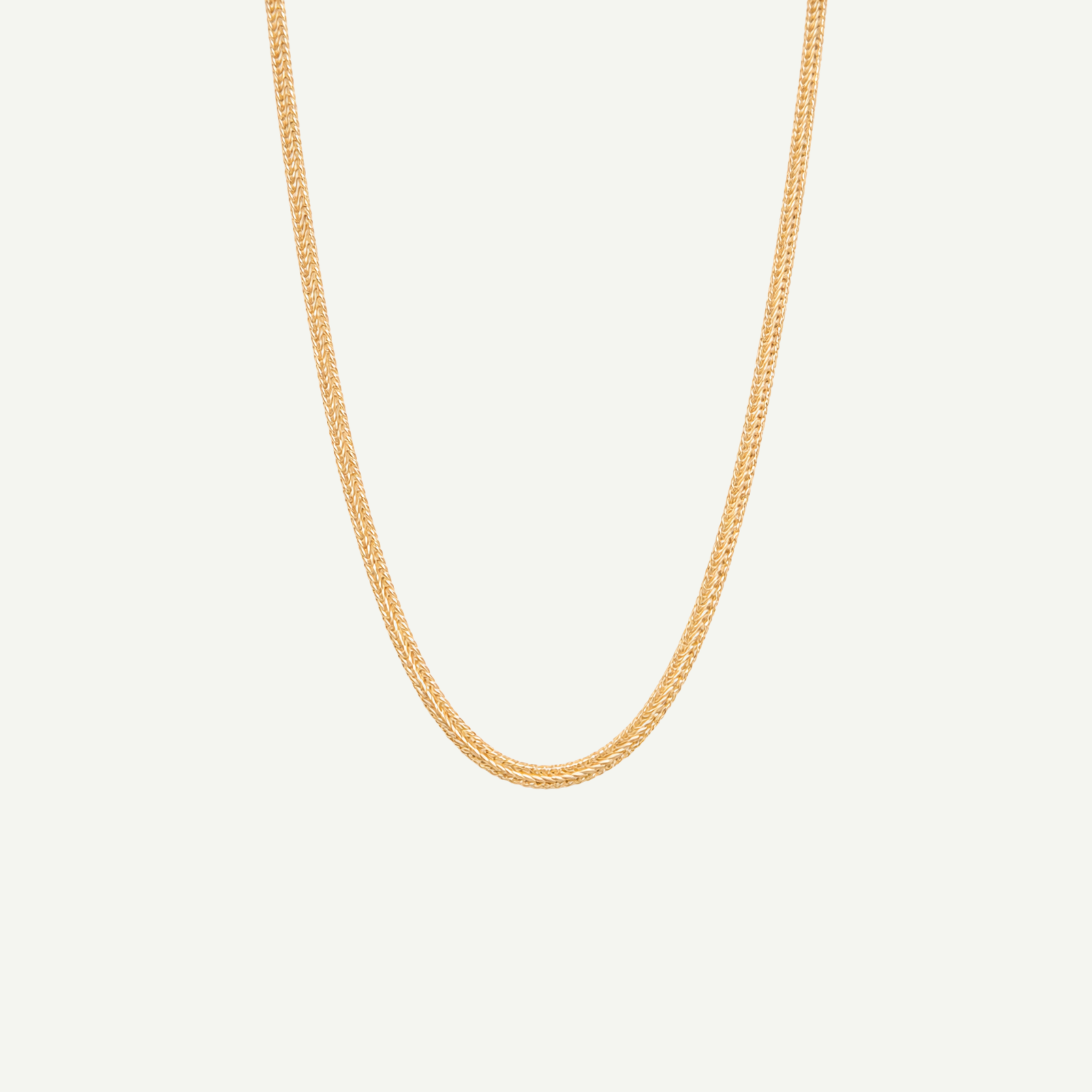 Gold chain necklace on a light gray background