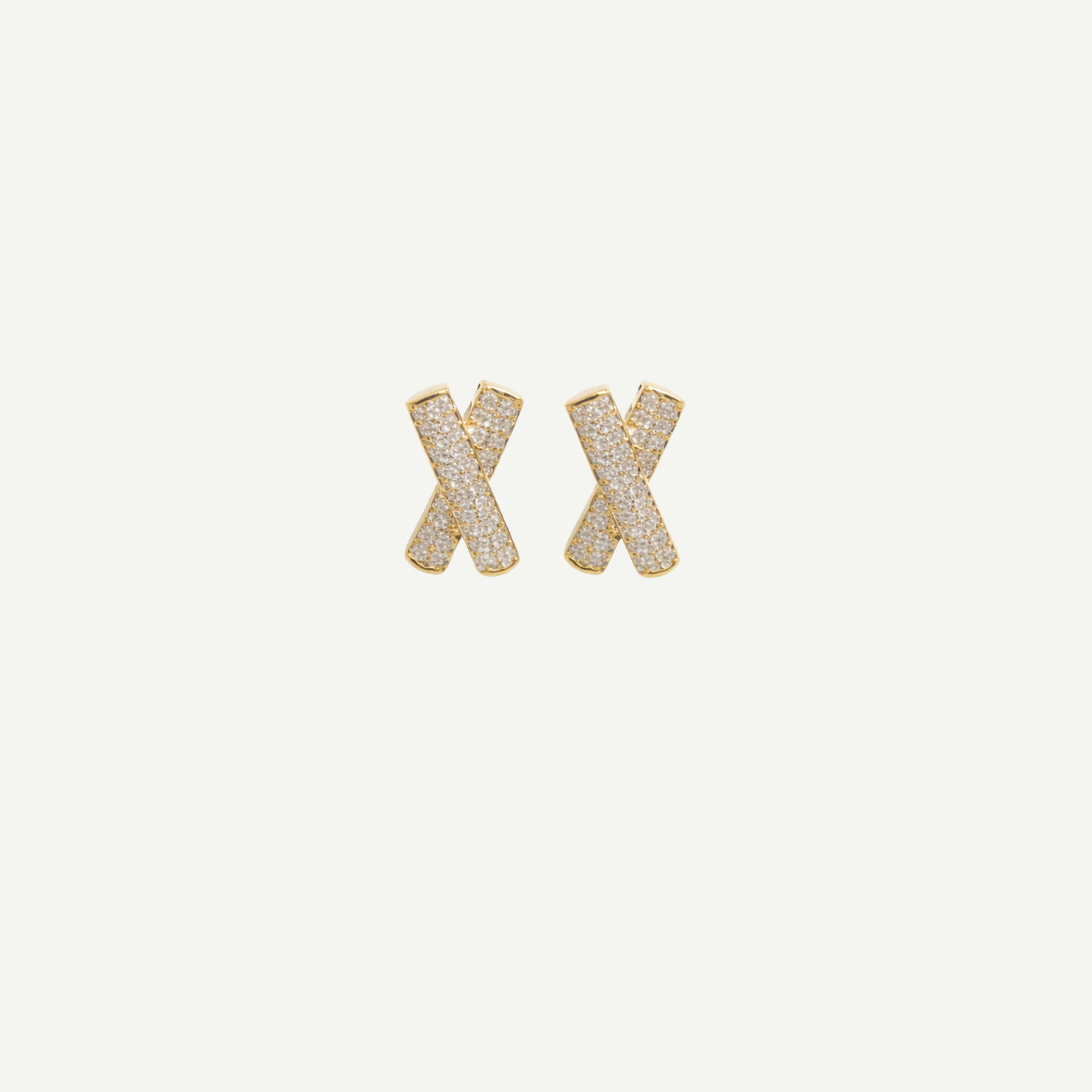 Gold 'X' shaped earrings on a light beige background