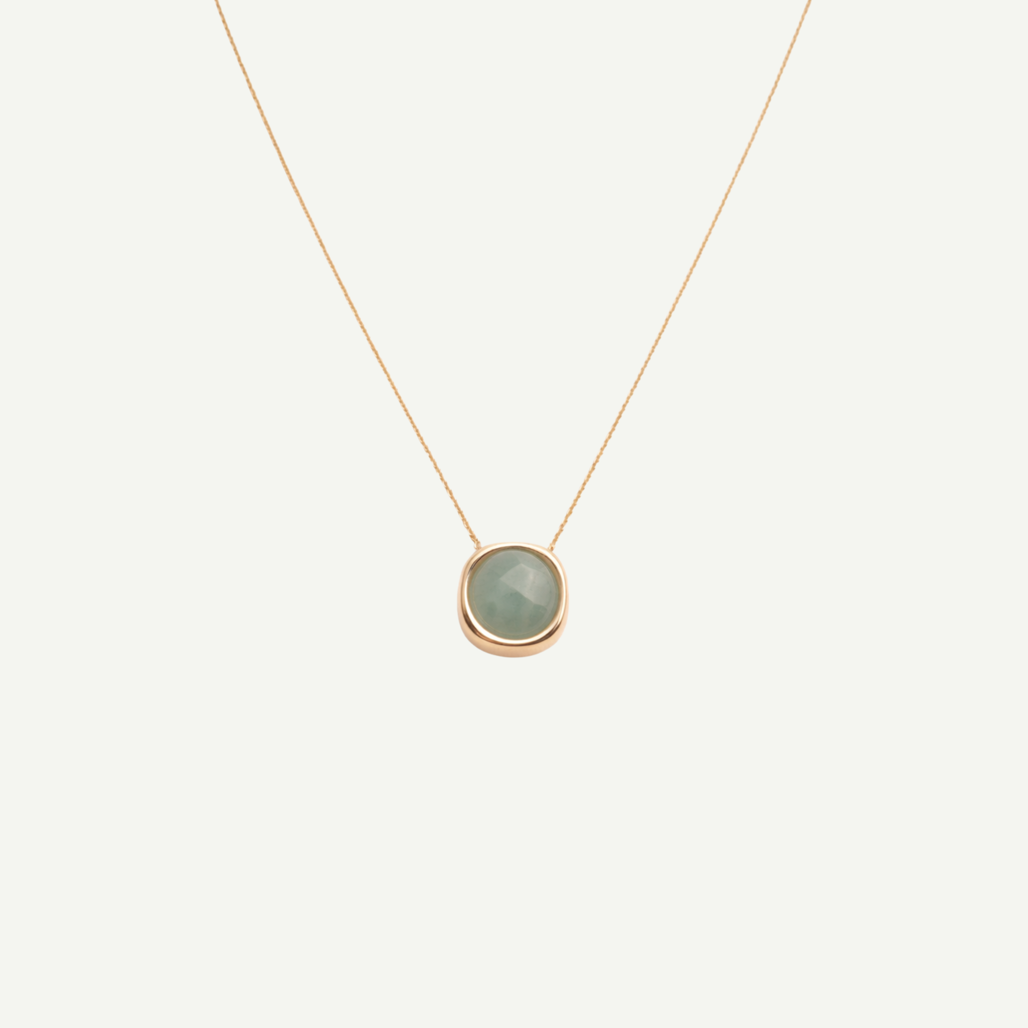 Necklace with a green pendant on a light beige background